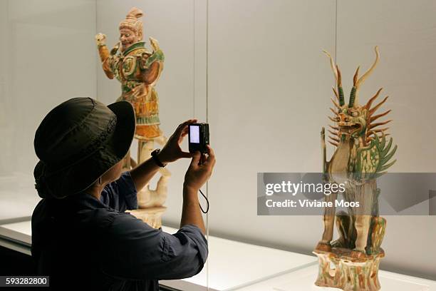Photography is permitted everywhere in the Shanghai Museum. A foreign visitor uses her tiny digital camera to photograph an ancient Chinese...
