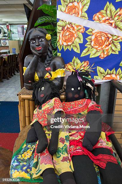 A welcoming comittee of two Black dolls and a statue in the traditional style of Bahia in front of a Bahia restaurant at the Nordestino fair in Sao...