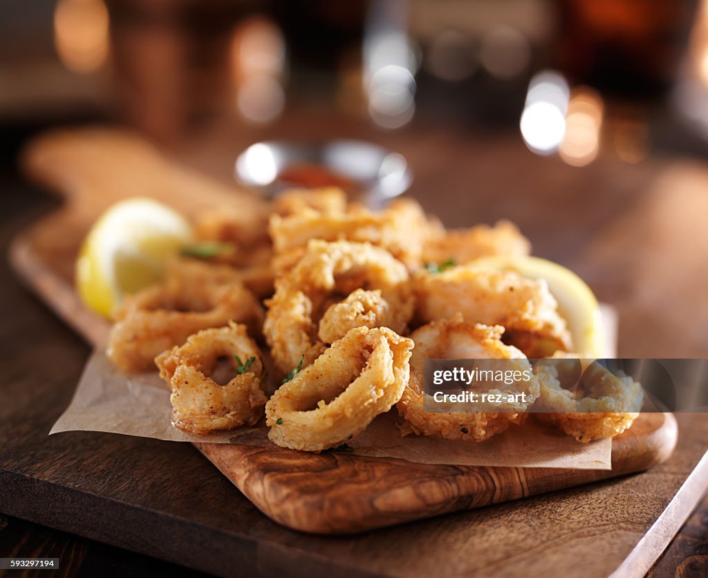Fried calimari rings on wooden tray with dipping sauce