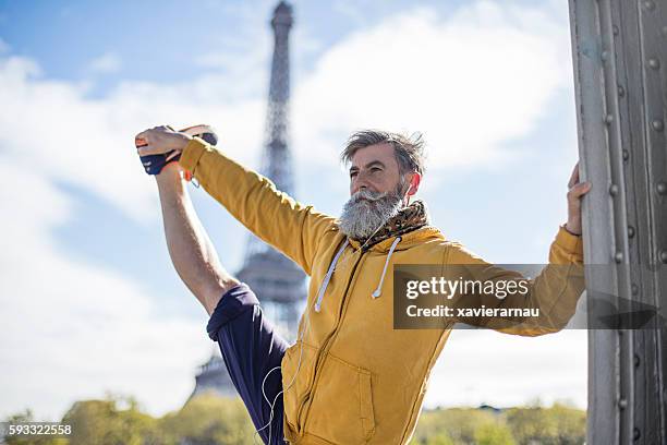 senior mann macht dehnübungen auf der straße - senior yoga stock-fotos und bilder