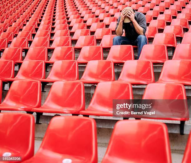 disappointed fan lingering at a stadium - nederlaag stockfoto's en -beelden