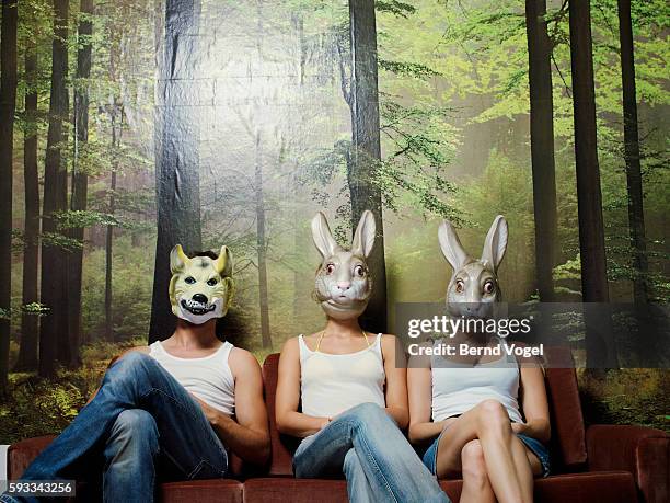 two women and man sitting on couch - wolf wallpaper stock-fotos und bilder
