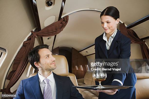 flight attendant serving businessman - millionnaire stock-fotos und bilder