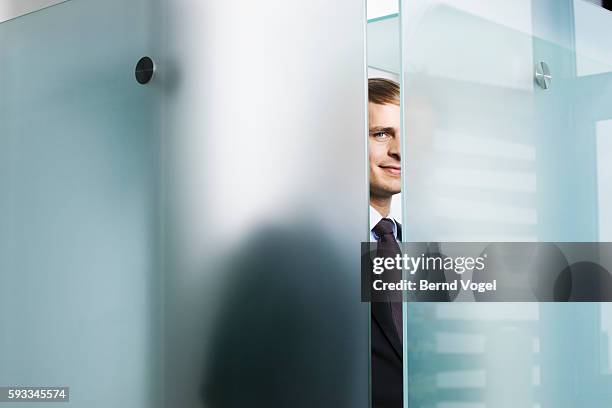 businessman peeking behind glass - frosted window stock pictures, royalty-free photos & images