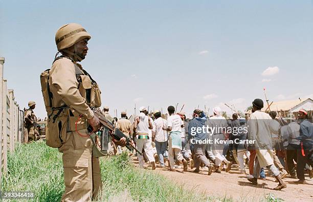 South African Defence Force soldier watches a Zulu Impi pass by in Soweto.