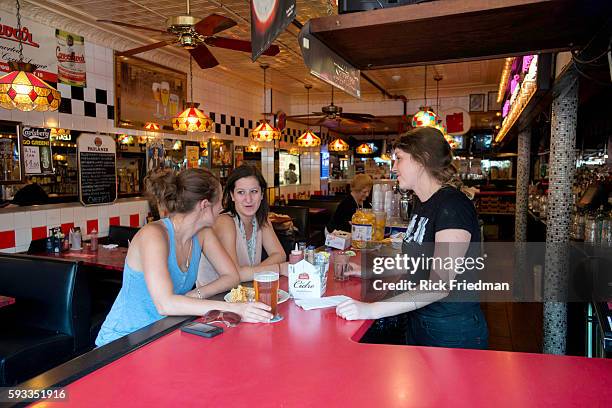 Bartender Alli Connolly at Charlie's Kitchen in Harvard Sq, Cambridge, MA on August 21, 2013 with customers Alix Easton of Brighton and Nina Krane of...