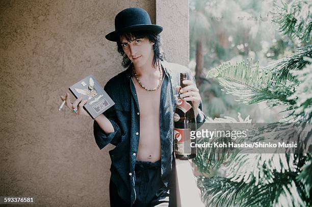 Izzy Stradlin Guns N' Roses holding shield for ML popularity vote and sake at a hotel, unknown, 1988.