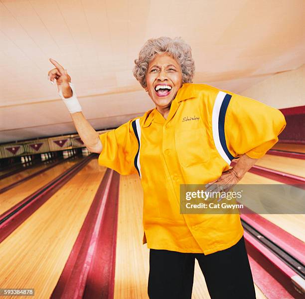 senior woman celebrating at bowling alley - bowling alley stock pictures, royalty-free photos & images