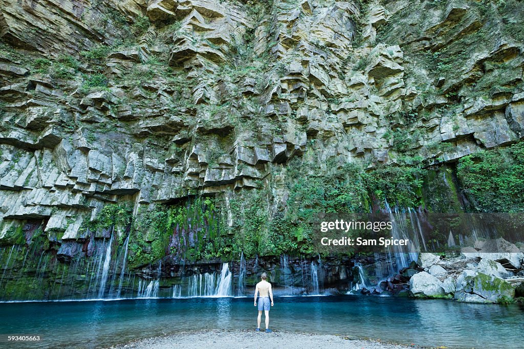 Man looking at beautiful waterfall lagoon