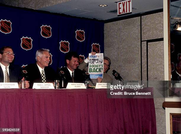 Robert O. Naegele Jr. Owner of the Minnesota Wild holds a newspaper that shows hockey will be back in Minnesota in the year 2000 as Craig L. Leipold,...