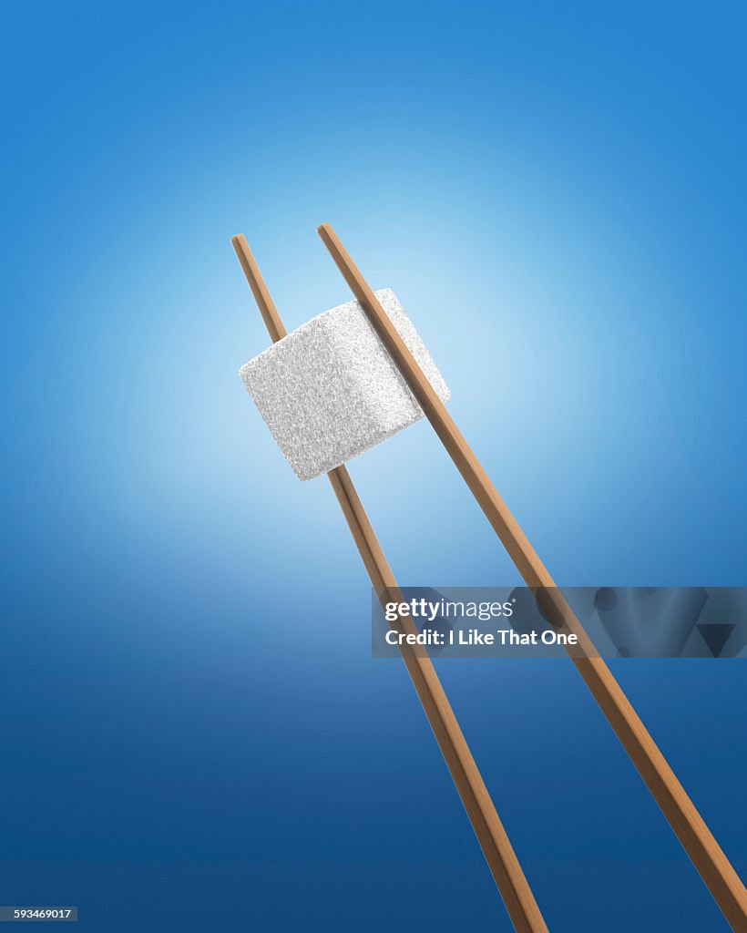 Chopsticks holding a white sugar cube