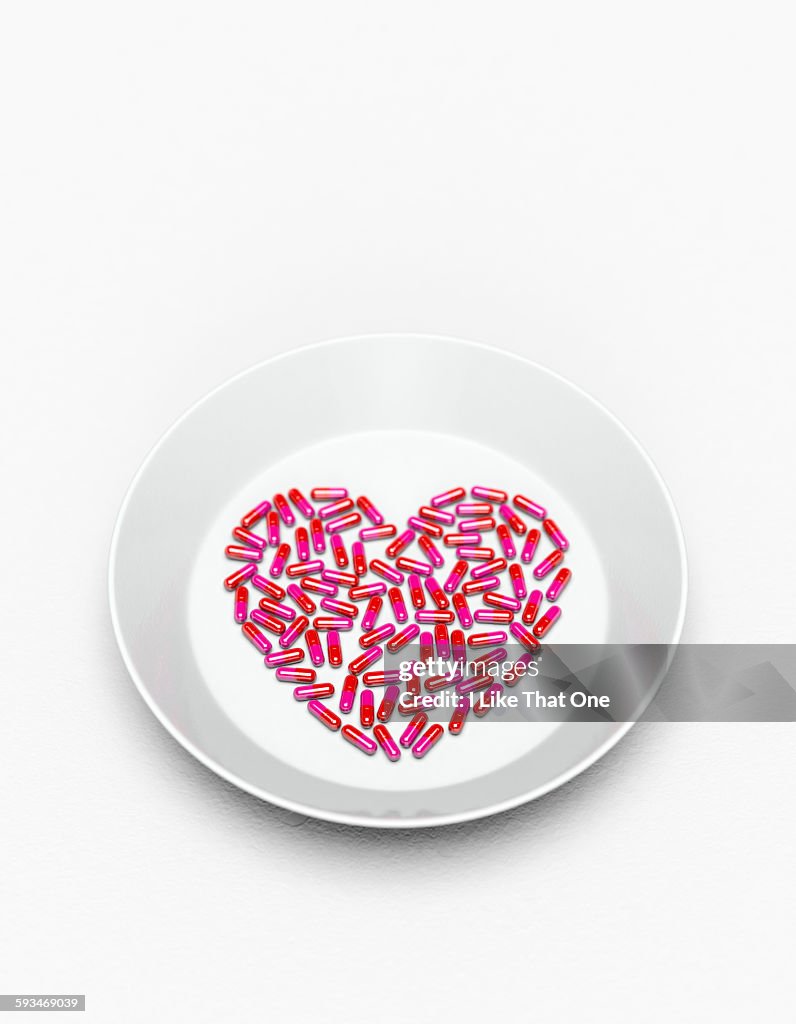 Pills in a heart shape on a white plate
