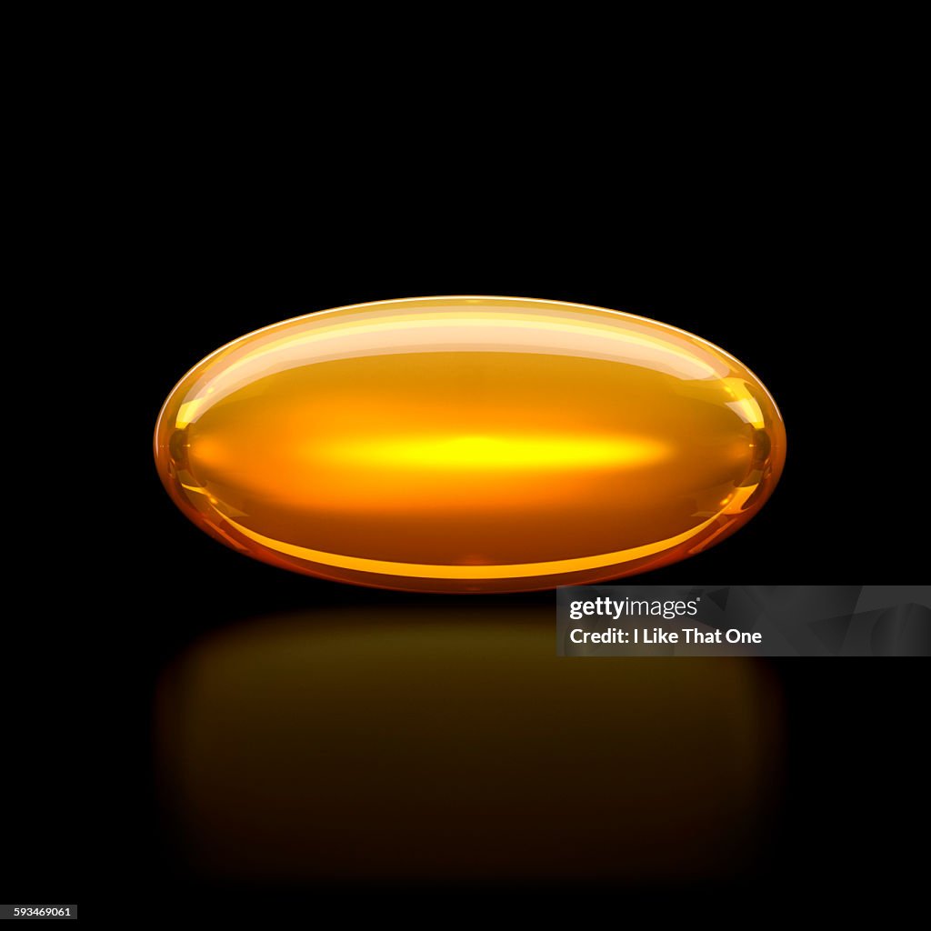 Oil / medication pill capsule on black surface