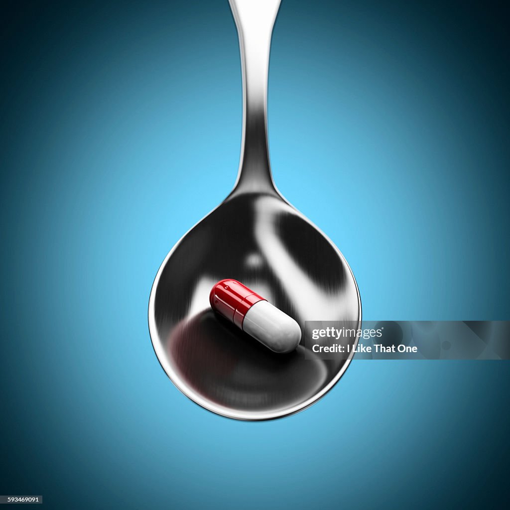 Teaspoon holding a red and white pill / capsule