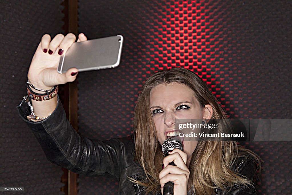 Girl singing into a microphone by making a selfie