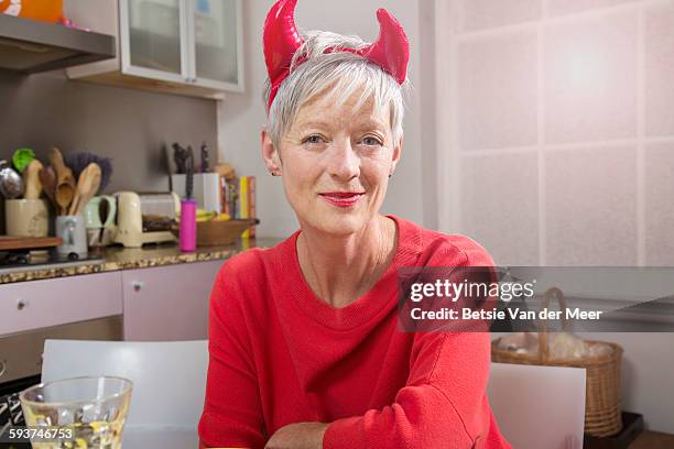 senior woman dressed up as devil sitting at dinner - party with the devil stock pictures, royalty-free photos & images