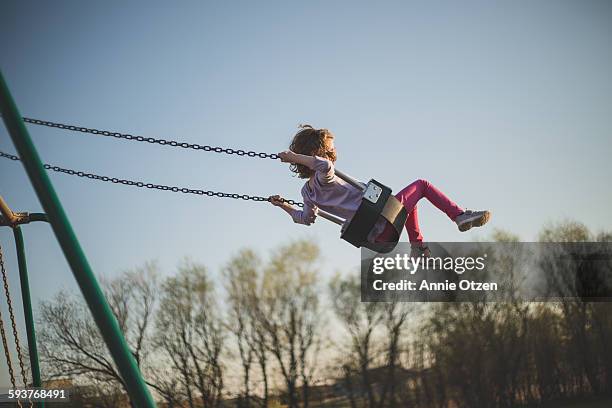 girl swinging high into the sky - schaukel stock-fotos und bilder