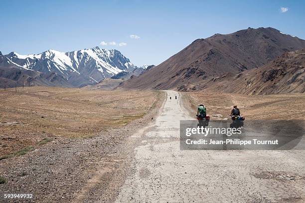 four friends cycling across the pamirs mountains of tajikistan (central asia) during a world tour by bicycle - silk road stock pictures, royalty-free photos & images