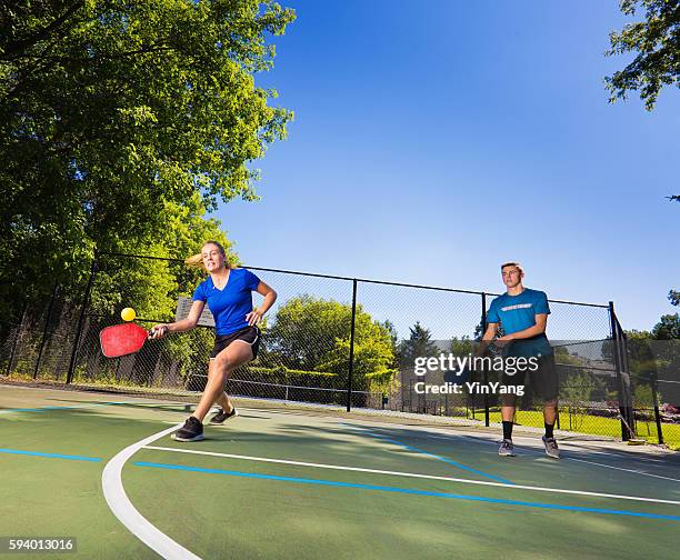 young man and woman pickleball player playing pickleball in court - bat stockfoto's en -beelden