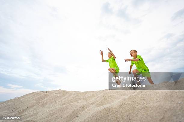 boys jumping in sandy beach - salto em comprimento imagens e fotografias de stock
