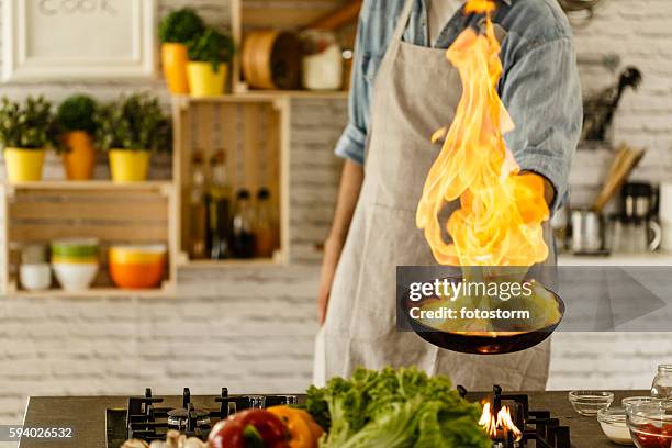 man cooking with fire in kitchen - homme fier stock pictures, royalty-free photos & images