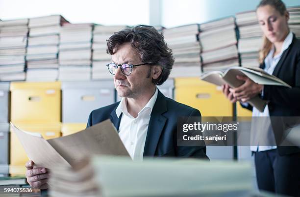 due colleghi che guardano le scartoffie in ufficio - burocrazia foto e immagini stock
