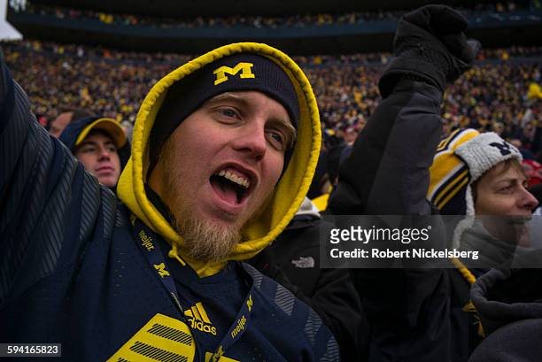 Unidentified fans and alumni of the University of Michigan cheer their football team during the traditional Big Ten game over the Thanksgiving...