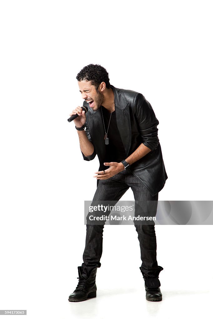 Man standing in studio singing into microphone