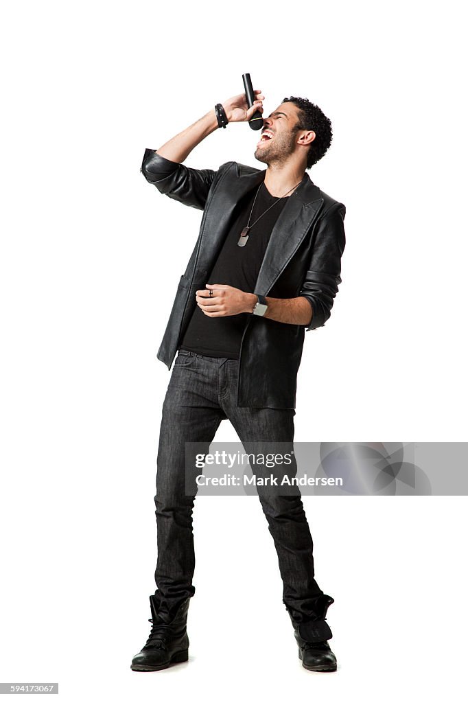 Man standing in studio singing into microphone