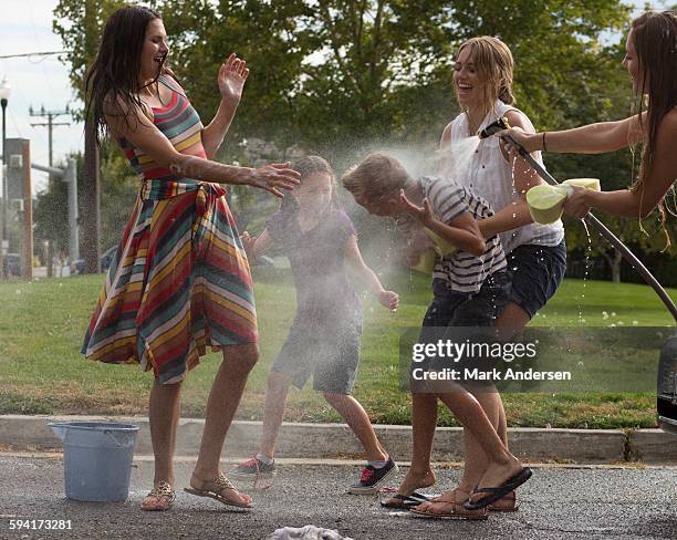 wet laughing family playing in spraying water hose in park - two kids playing with hose stock pictures, royalty-free photos & images
