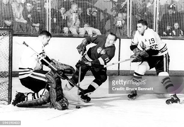 Goalie Glenn Hall of the Chicago Blackhawks makes the save on Jack McIntyre of the Detroit Red Wings as Hall's teammate Dollard St. Laurent helps...