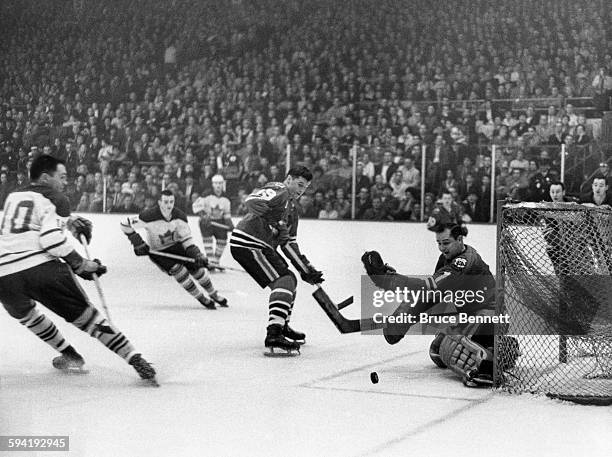 Goalie Glenn Hall of the Chicago Blackhawks looks to make the save on George Armstrong of the Toronto Maple Leafs as Al MacNeil of the Blackhawk...