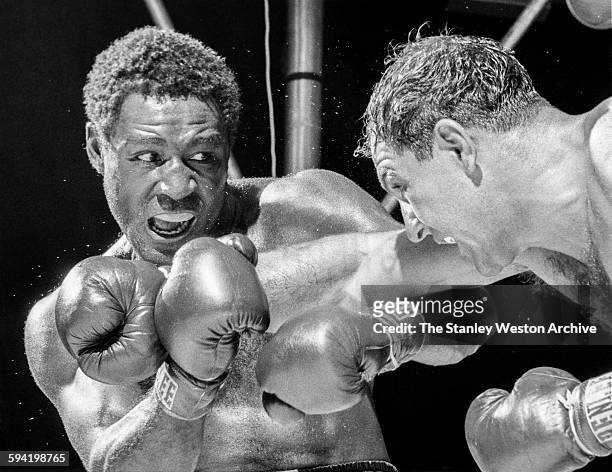 Defending heavyweight champion Rocky Marciano bulls into ex-champion Ezzard Charles, in the fifth round of bout. Marciano won by eighth-round...