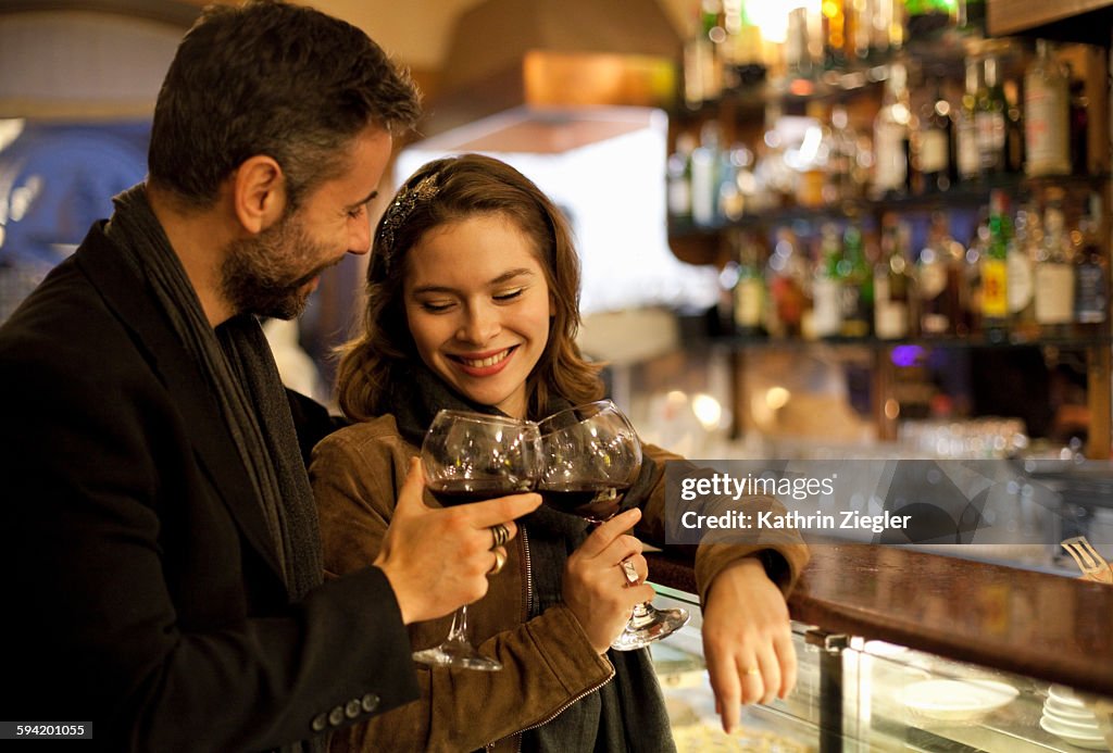 Couple toasting with red wine at bar