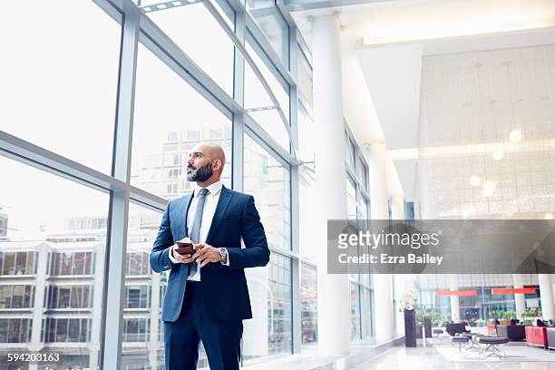 businessman looking out a window in modern office - business person looking thoughtful stock pictures, royalty-free photos & images