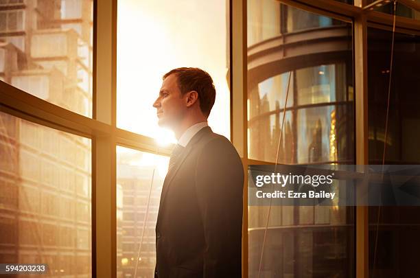 businessman looking out over the city at sunrise. - business man profile fotografías e imágenes de stock