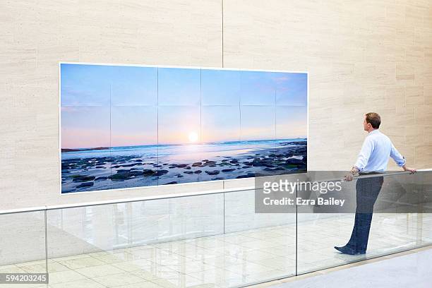 businessman admires a sunset printed on paper. - prodotto d'arte e artigianato foto e immagini stock