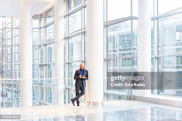 businessman using his phone in a modern office - building lobby stock pictures, royalty-free photos & images