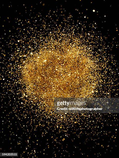 golden glitter explosion - gold particle stock pictures, royalty-free photos & images