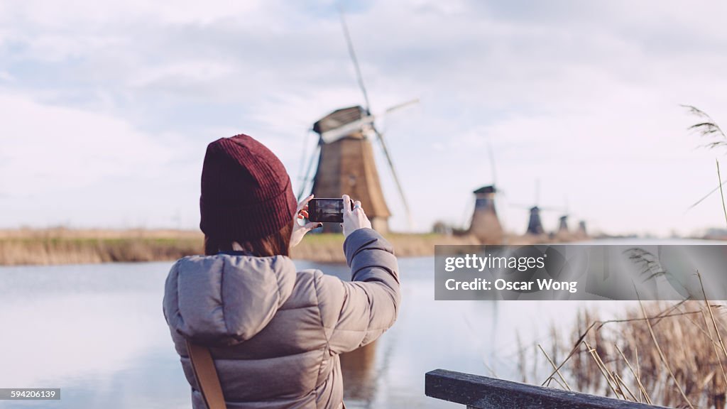 Girl taking picture of windmills with smartphone