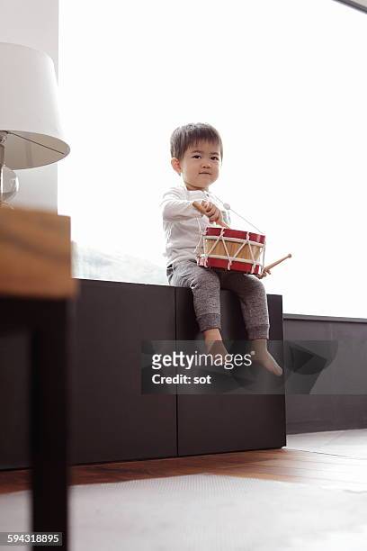 baby boy playing toy drum in living room - toddler musical instrument stock pictures, royalty-free photos & images