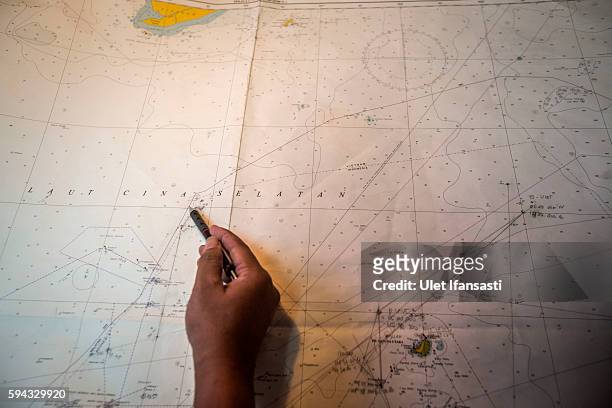 Security ship crew of Ministry of Maritime Affairs and Fisheries, works on a map during a patrol in the South China Sea on August 17, 2016 in Natuna,...