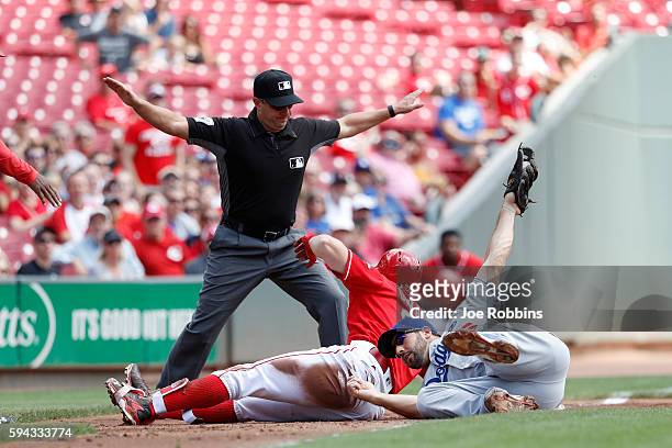 Adam Duvall of the Cincinnati Reds slides into third base ahead of the tag by Rob Segedin of the Los Angeles Dodgers with an RBI triple in the first...