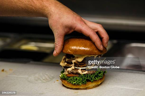 Chef places a bun on top of an Obama Burger at John's Fish Market in Vineyard Haven, Mass., on the island of Martha's Vineyard, Aug. 18, 2016....