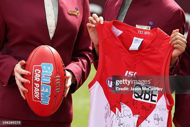 Qatar Airways flight attendants hold up a match ball and Swans jersey during a Sydney Swans AFL media announcement at Sydney Cricket Ground on August...