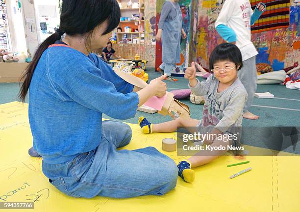 Photo taken May 21 in Hiroshima shows an elementary school student with an intellectual disability working on an art piece at afterschool daycare...