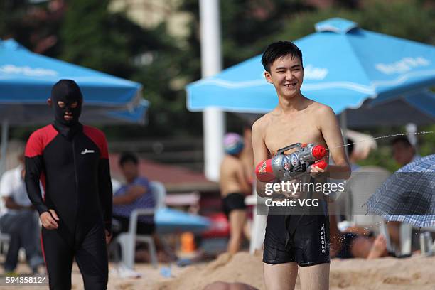 Man wearing a facekini walks on beach on August 22, 2016 in Qingdao, Shandong Province of China. People wear facekinis to protect themselves from...