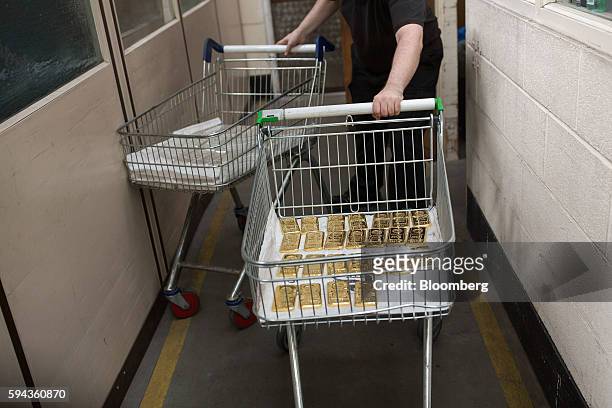 An employee moves 1 kilo gold and silver bars on a shopping trollies at the Baird & Co. Ltd. Precious metals refinery in London, U.K., on Wednesday,...