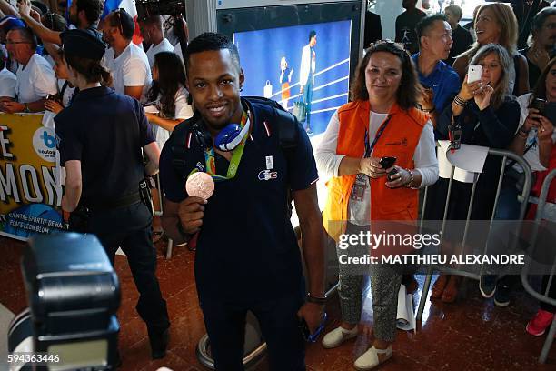 French hurdler and bronze medallist Dimitri Bascou shows his medal at the Roissy-Charles-De-Gaulle airport as he arrives in France with the olympic...