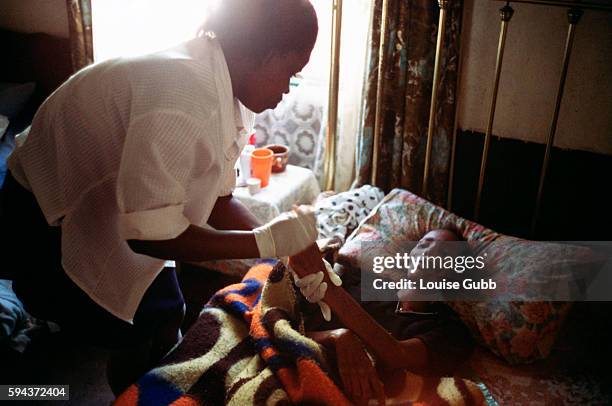 Hospital caregiver makes her first visit to Pumzile, age 20, who has contracted AIDS and is now bedridden, has partial paralysis in the legs, and has...